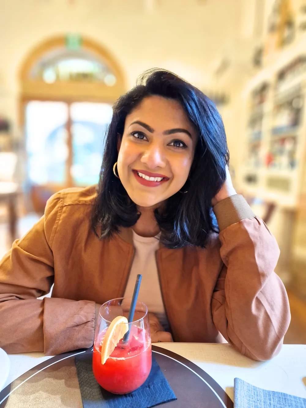 Sonia Chowdhury, Nutritional Therapy Practitioner, smiling at a café table